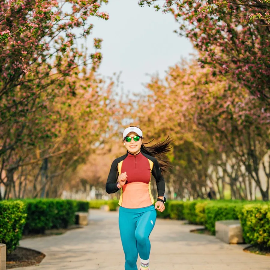 Smiling woman jogging on a tree-lined path